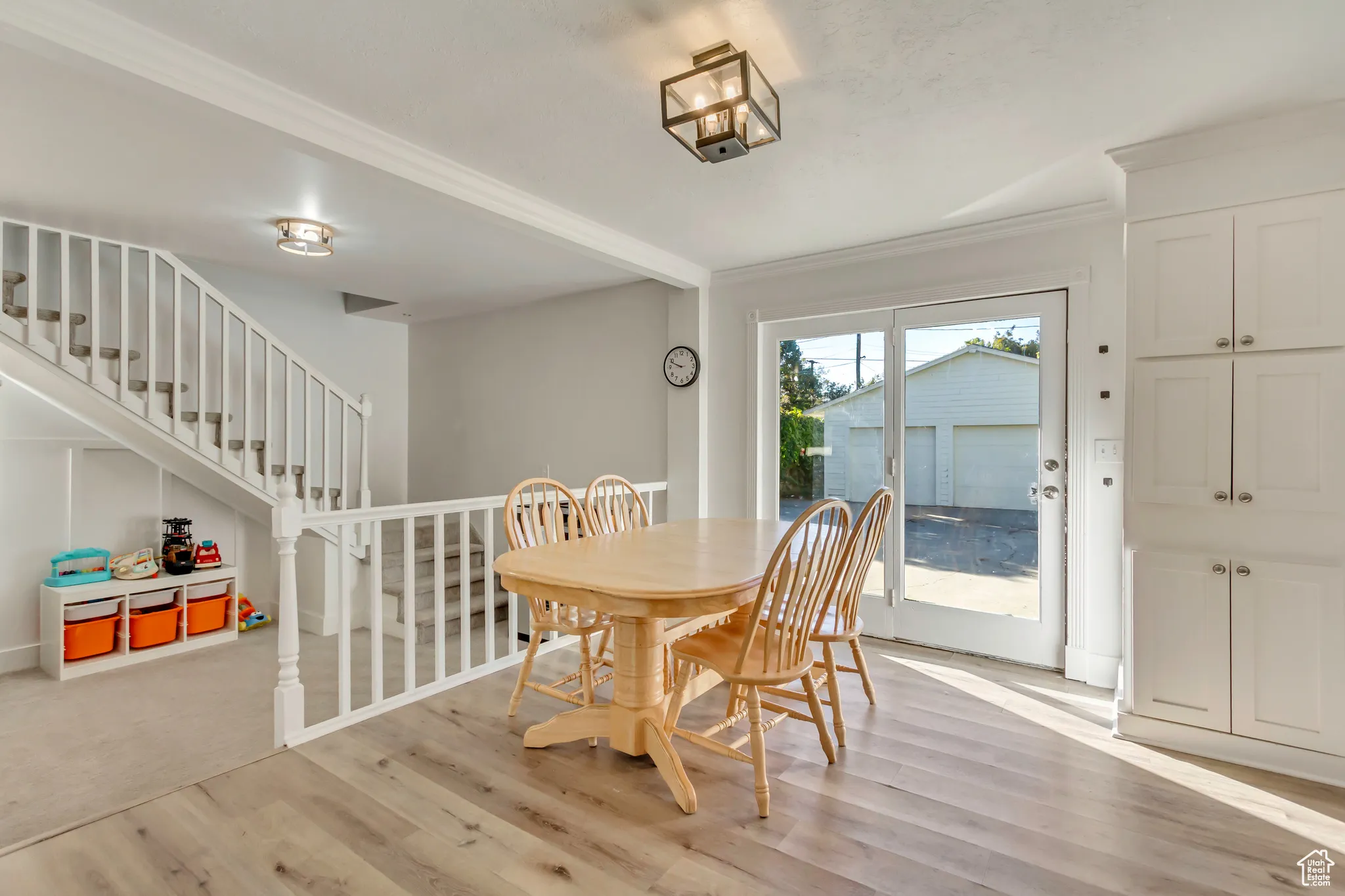 Dining room with light wood finished floors, crown molding, and stairs