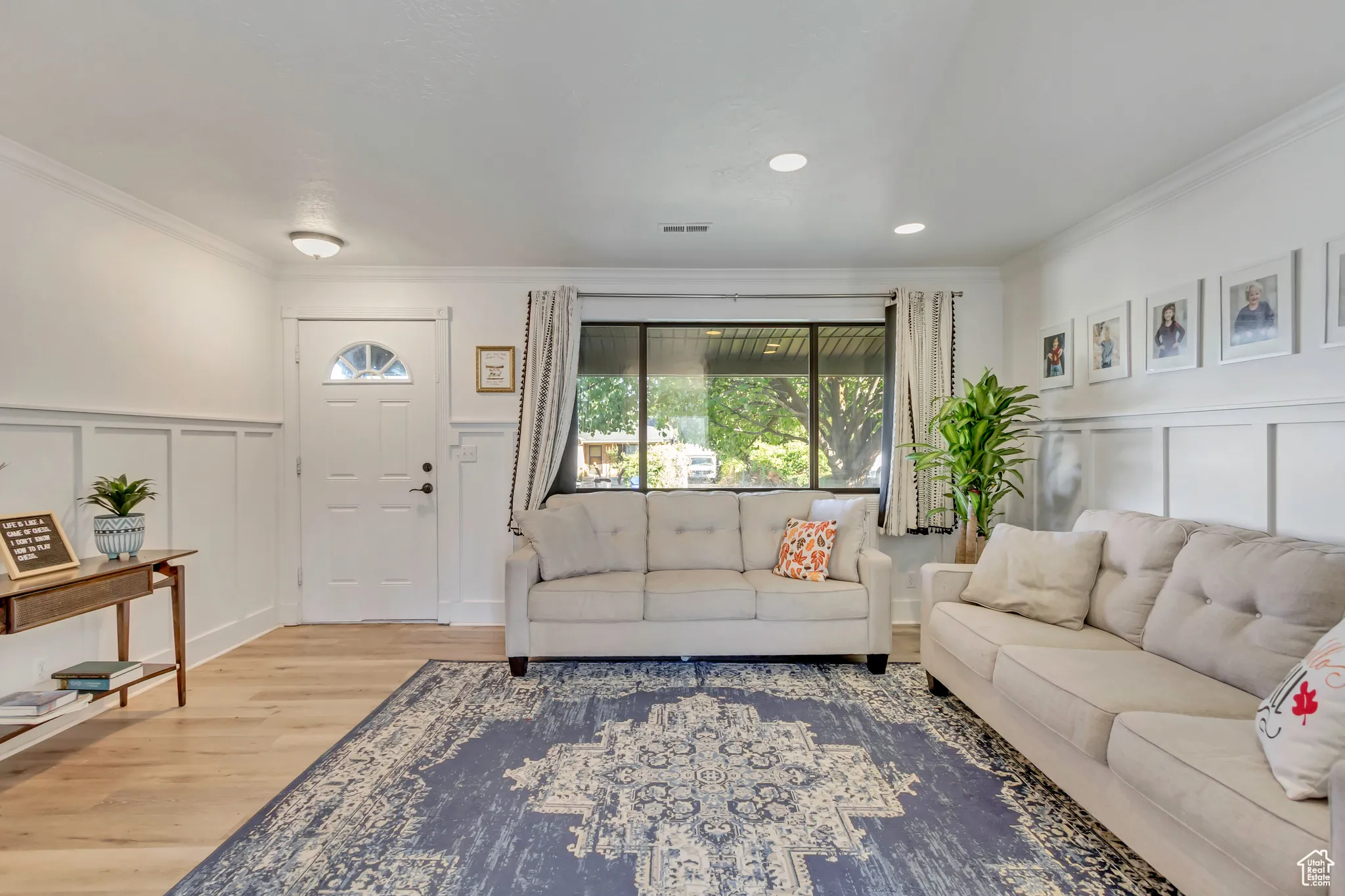 Living room featuring a decorative wall, a wainscoted wall, crown molding, wood finished floors, and recessed lighting