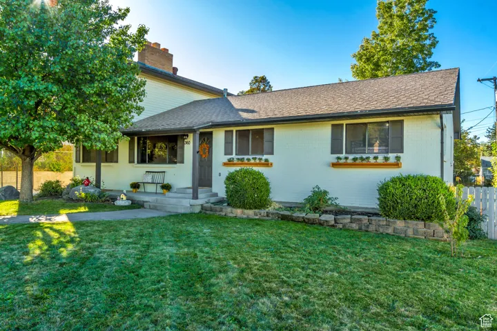 View of front of house with brick siding, roof with shingles, and a chimney