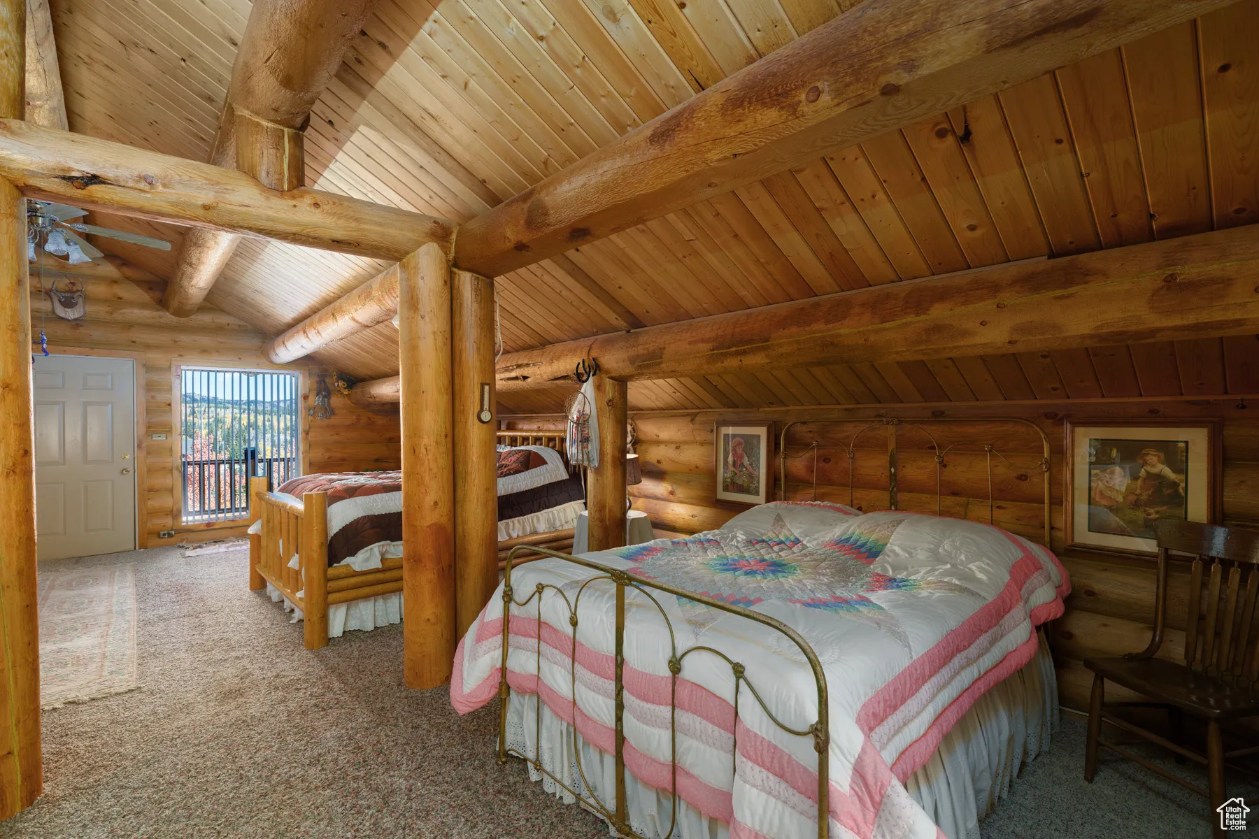 Carpeted bedroom with rustic walls and a wooden ceiling with exposed beams