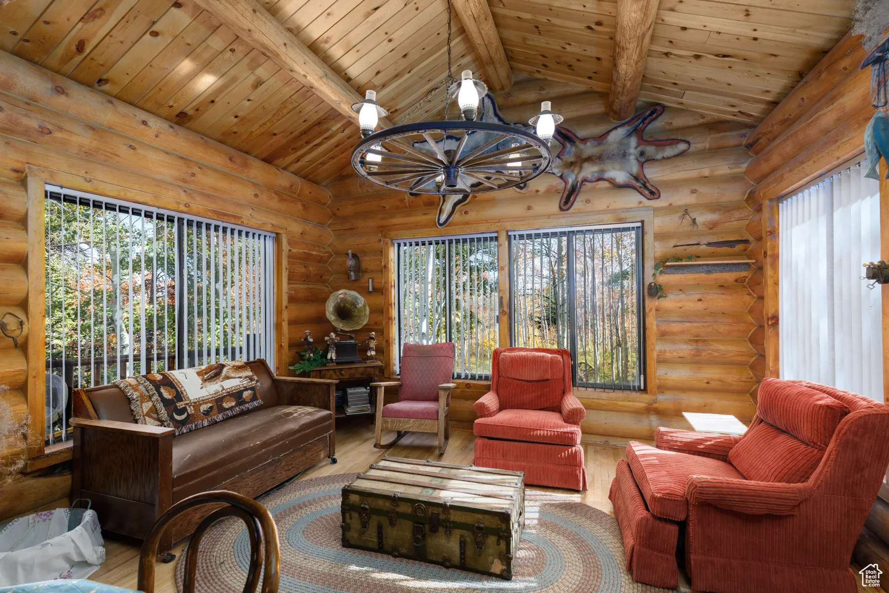 Living room featuring wood ceiling, wood finished floors, log walls, and a chandelier
