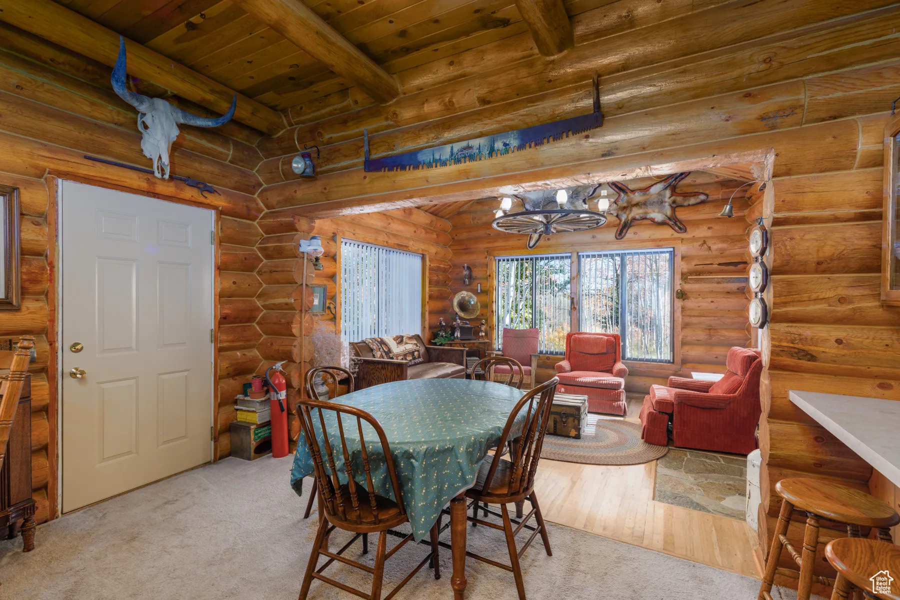 Dining space featuring a wooden ceiling with exposed beams, rustic walls, light wood finished floors, and light colored carpet