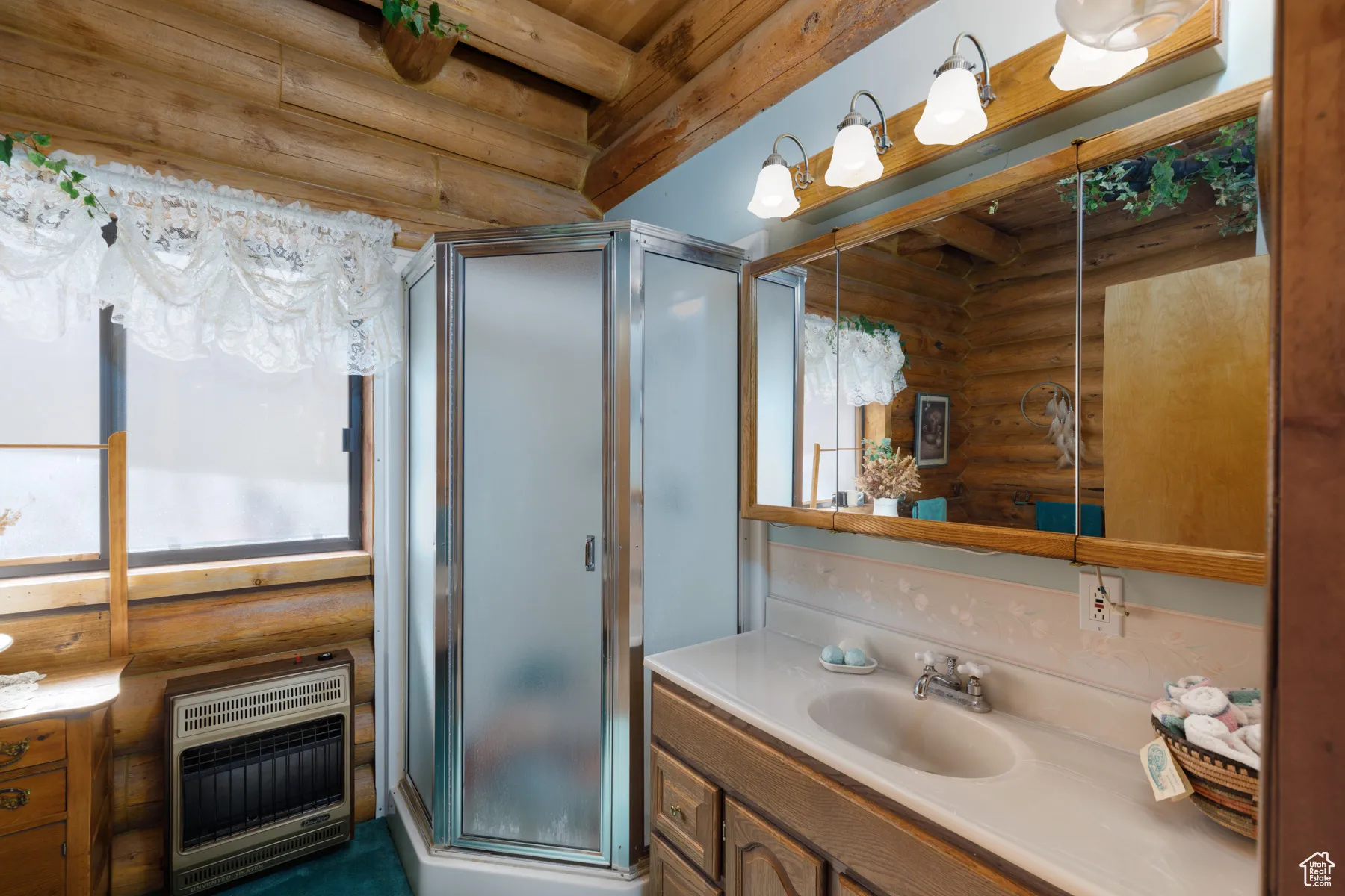 Bathroom featuring log walls, vanity, a shower stall, heating unit, and beam ceiling