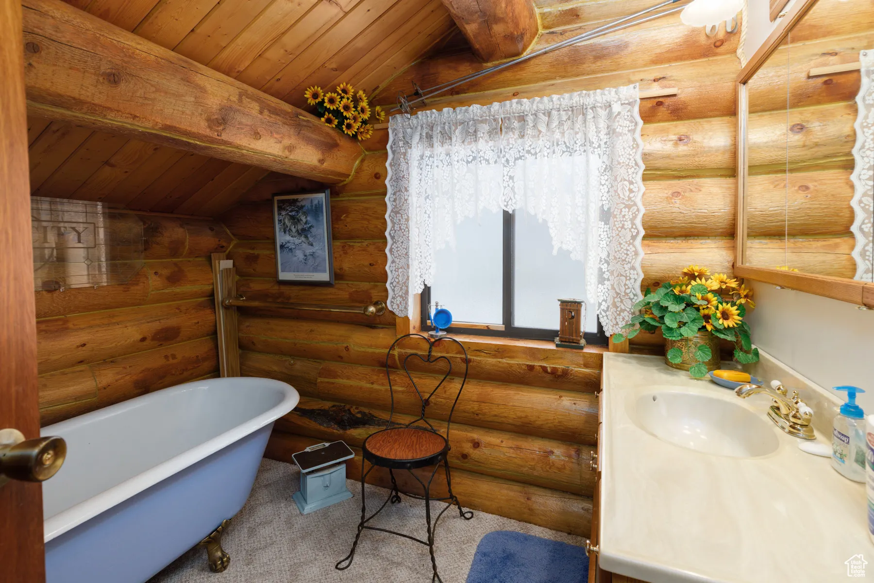 Bathroom with a soaking tub, wooden ceiling, log walls, and vanity