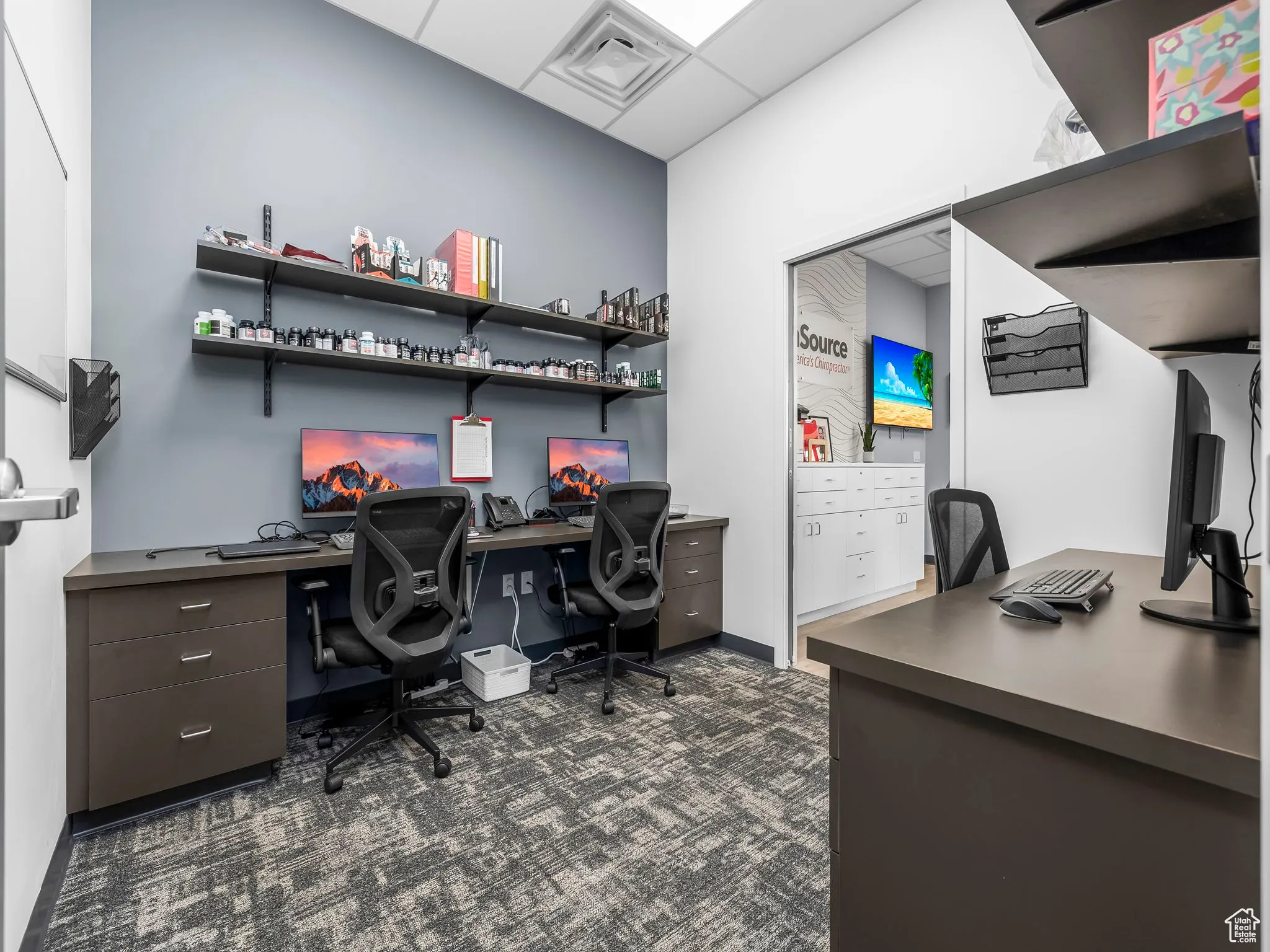 Office with dark carpet and a paneled ceiling