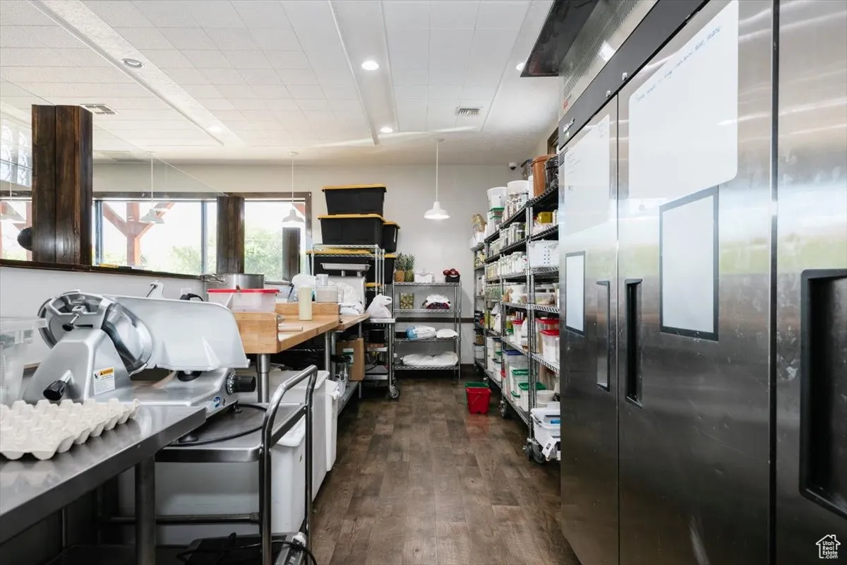 Kitchen with stainless steel refrigerator, dark wood finished floors, and decorative light fixtures