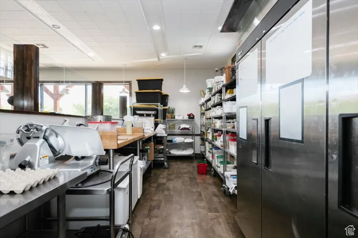 Kitchen with stainless steel refrigerator, dark wood finished floors, and decorative light fixtures