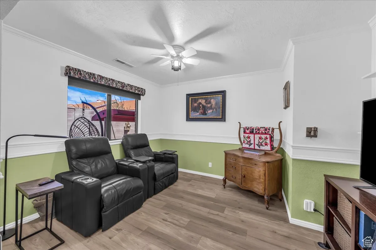 Living area featuring wood finished floors, a textured ceiling, ornamental molding, and ceiling fan