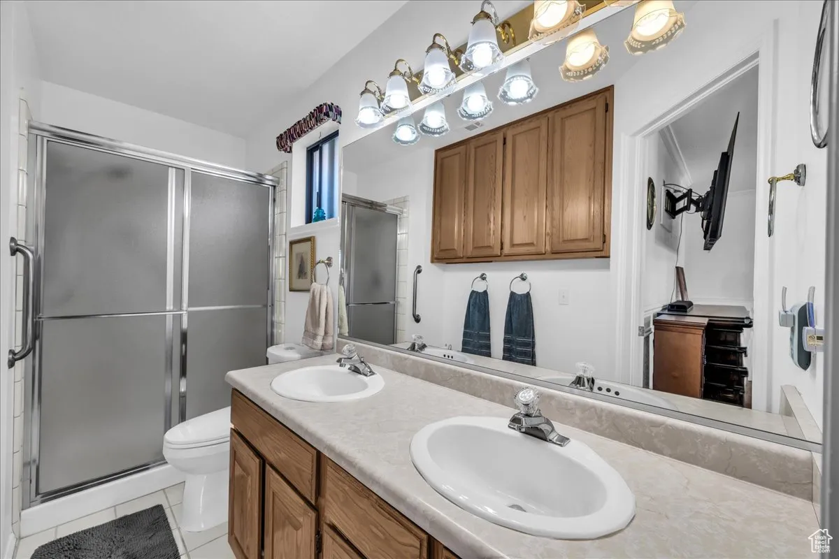 Full bathroom with a shower stall, light tile patterned flooring, and double vanity
