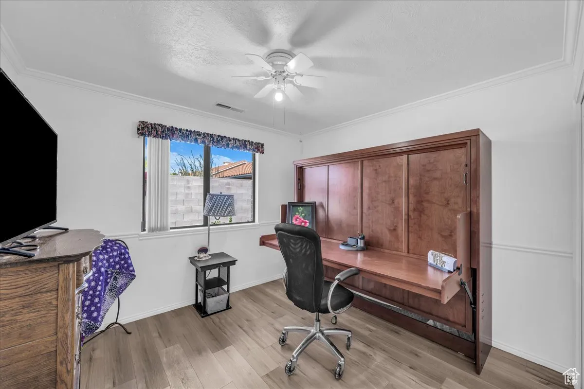 Office area featuring a textured ceiling, light wood-style floors, ceiling fan, and crown molding
