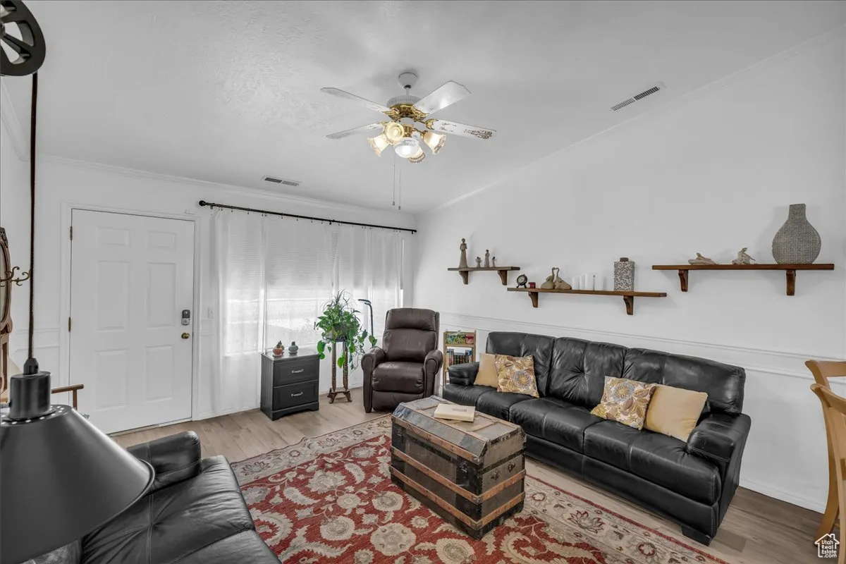 Living area featuring ornamental molding, wood finished floors, ceiling fan, and a textured ceiling