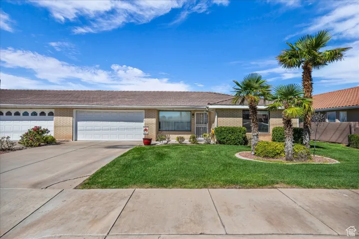 Ranch-style house featuring brick siding, a front yard, concrete driveway, and a garage