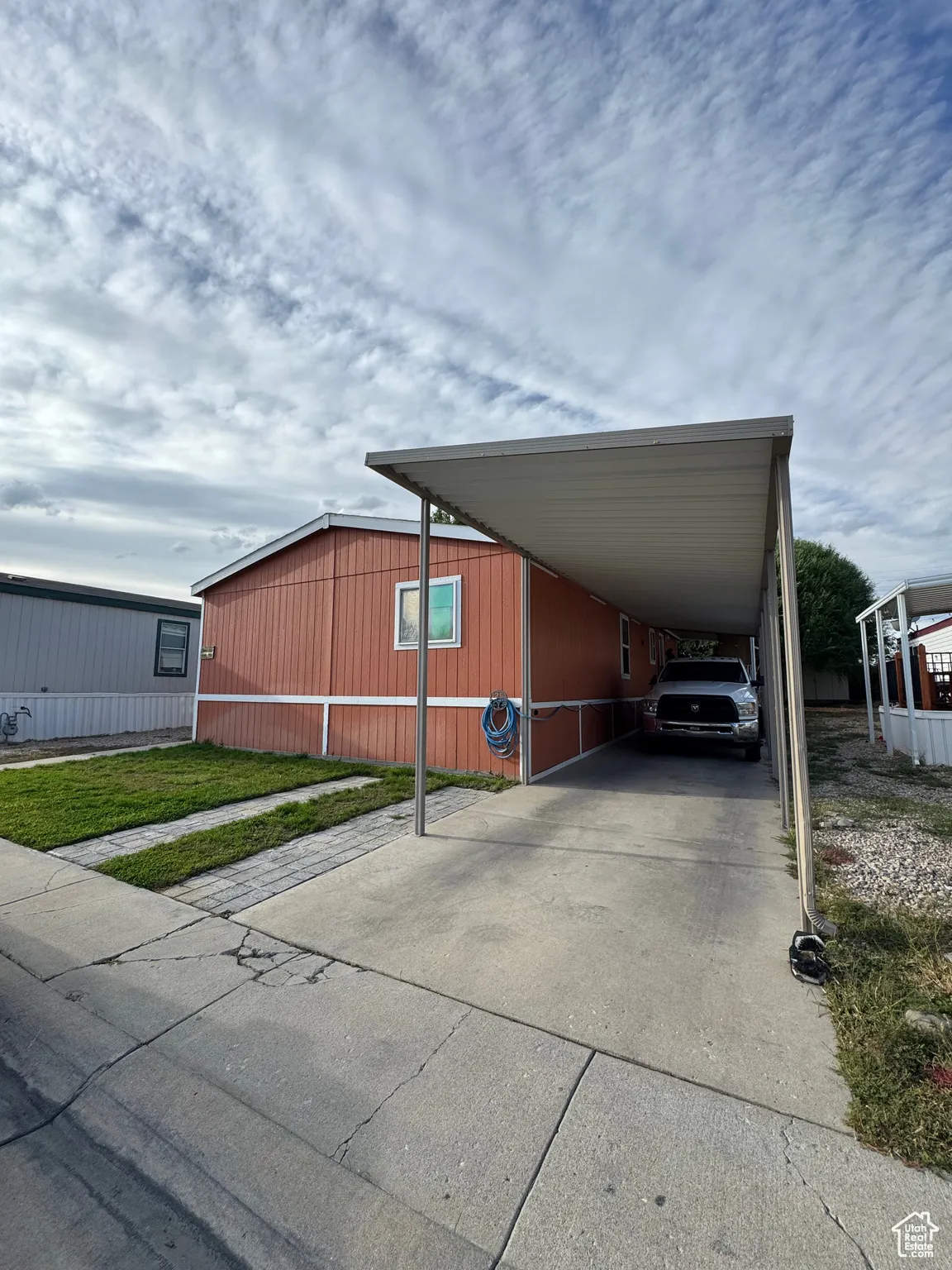 View of parking with driveway and a carport