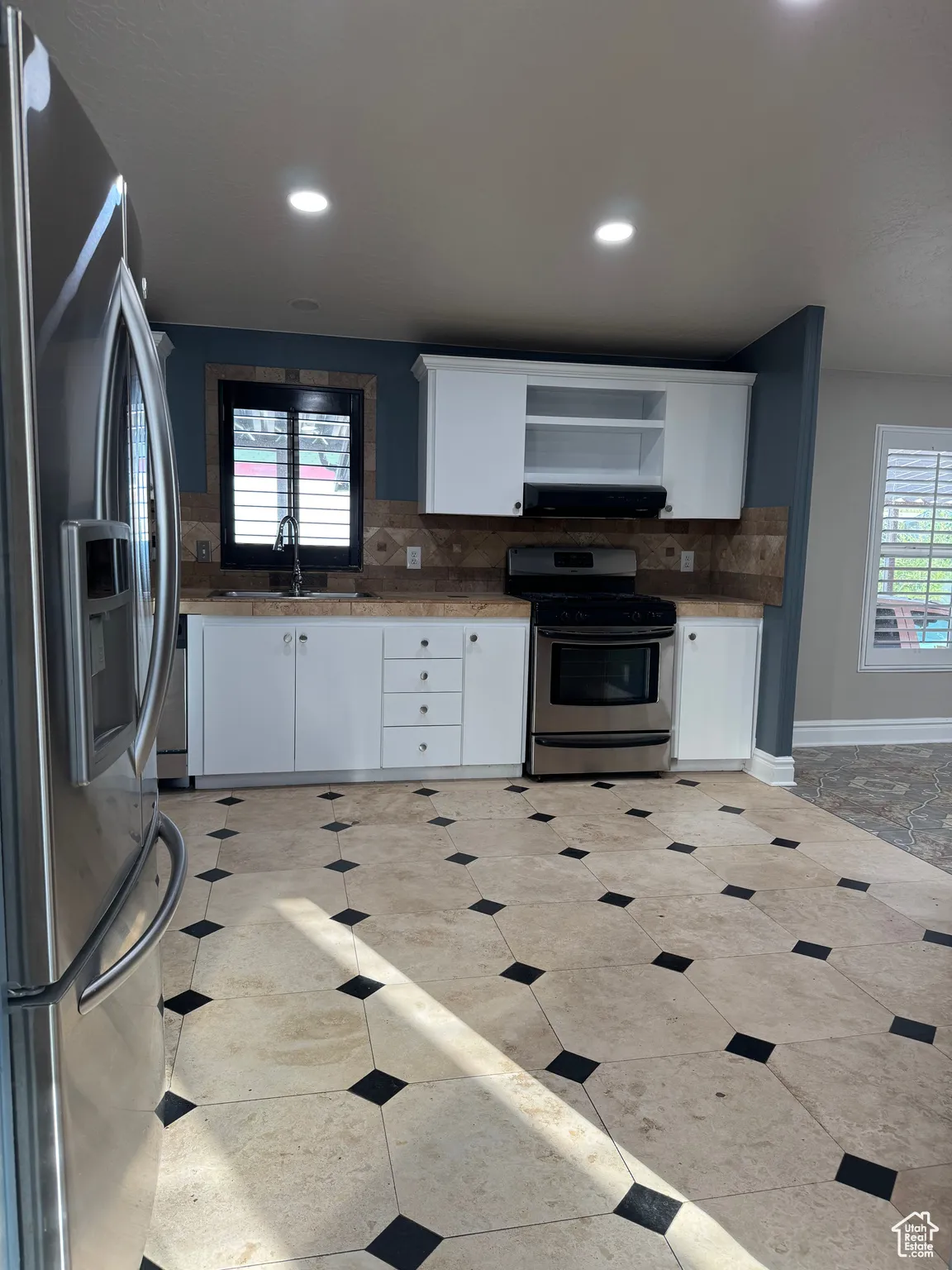 Kitchen with decorative backsplash, white cabinetry, appliances with stainless steel finishes, open shelves, and recessed lighting