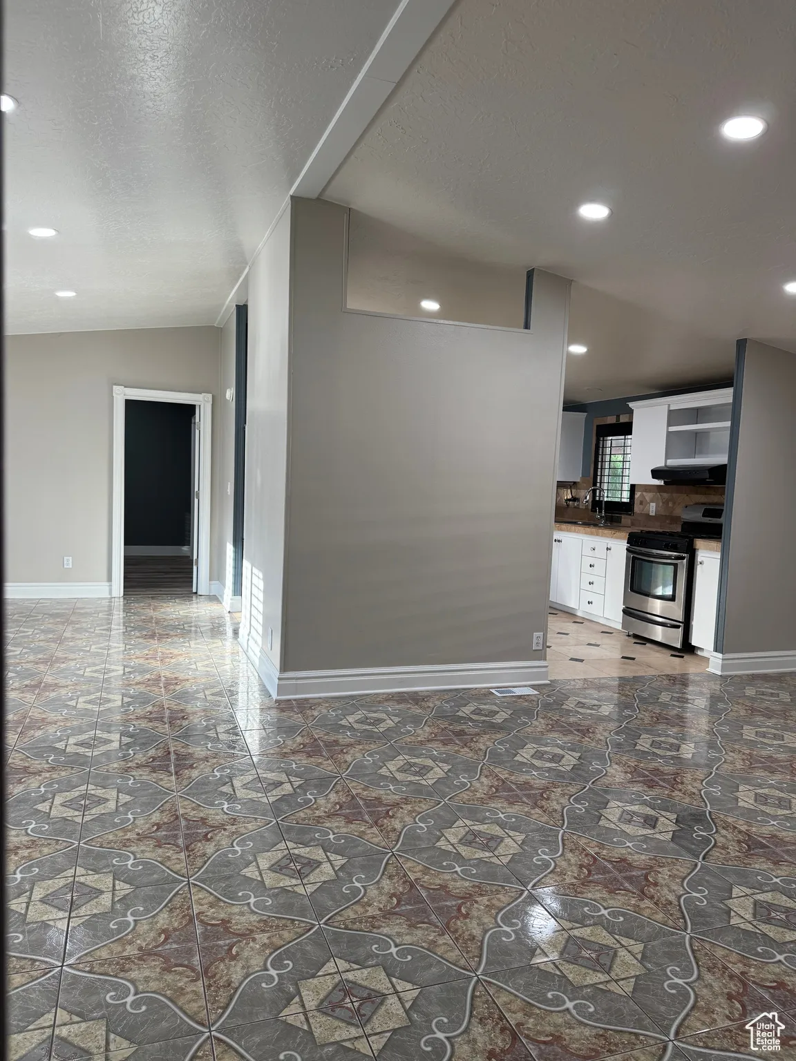 Kitchen featuring recessed lighting, stainless steel gas range oven, a textured ceiling, white cabinets, and dark countertops