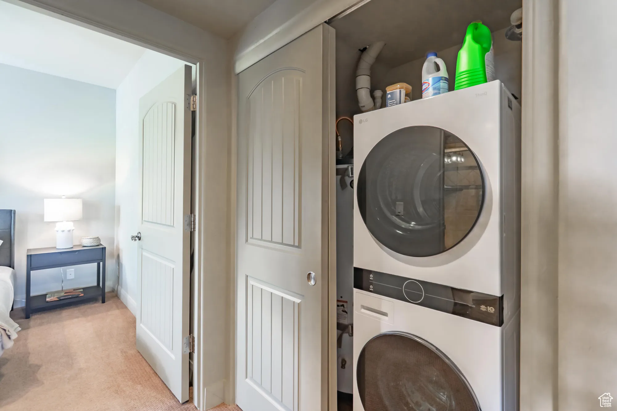 Laundry area featuring estacked washer and dryer and light colored carpet