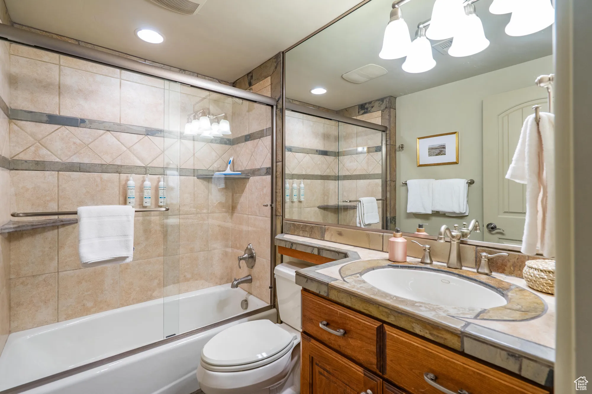 Bathroom featuring combined bath / shower with glass door, vanity, and recessed lighting