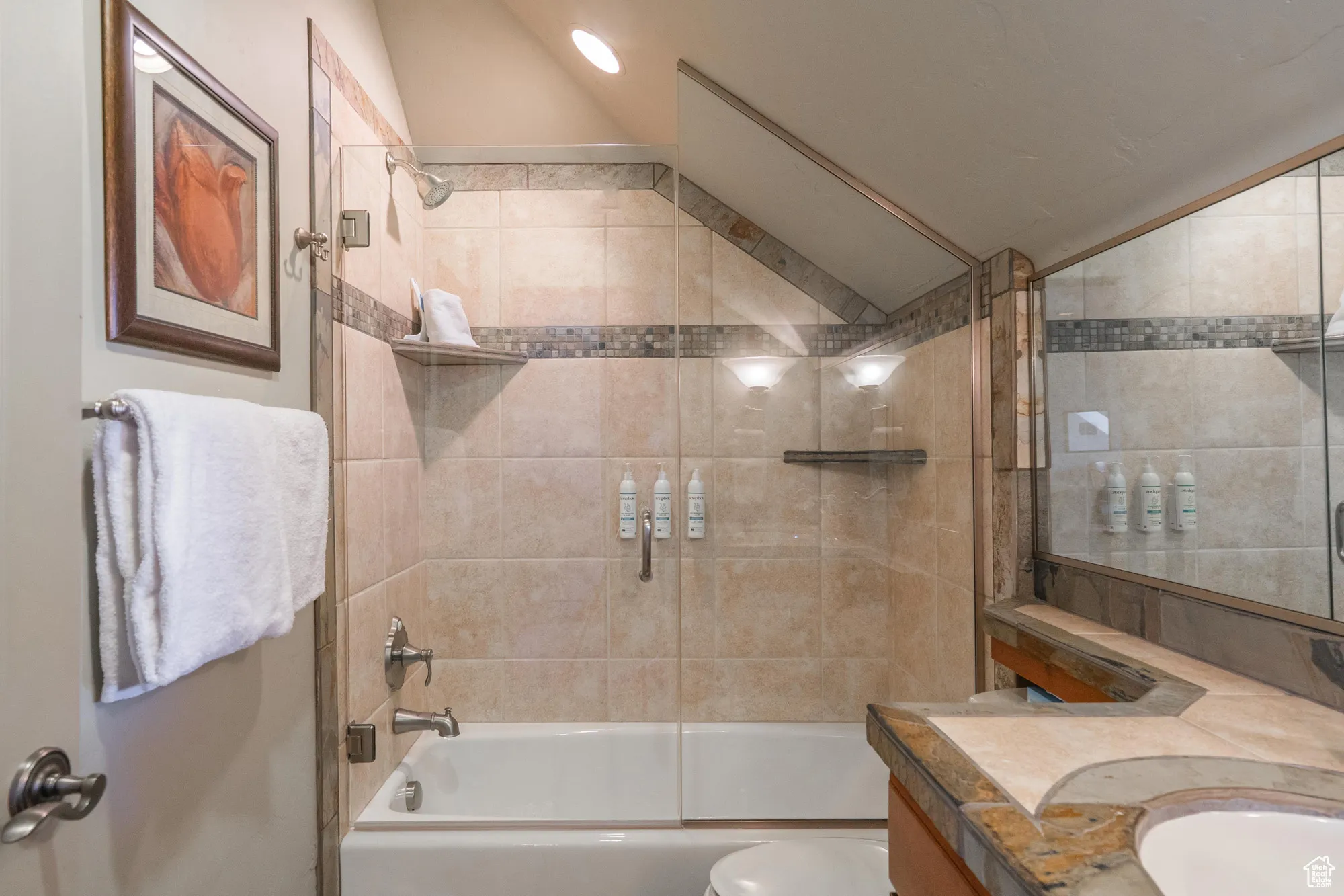 Bathroom featuring tub / shower combination, lofted ceiling, and vanity