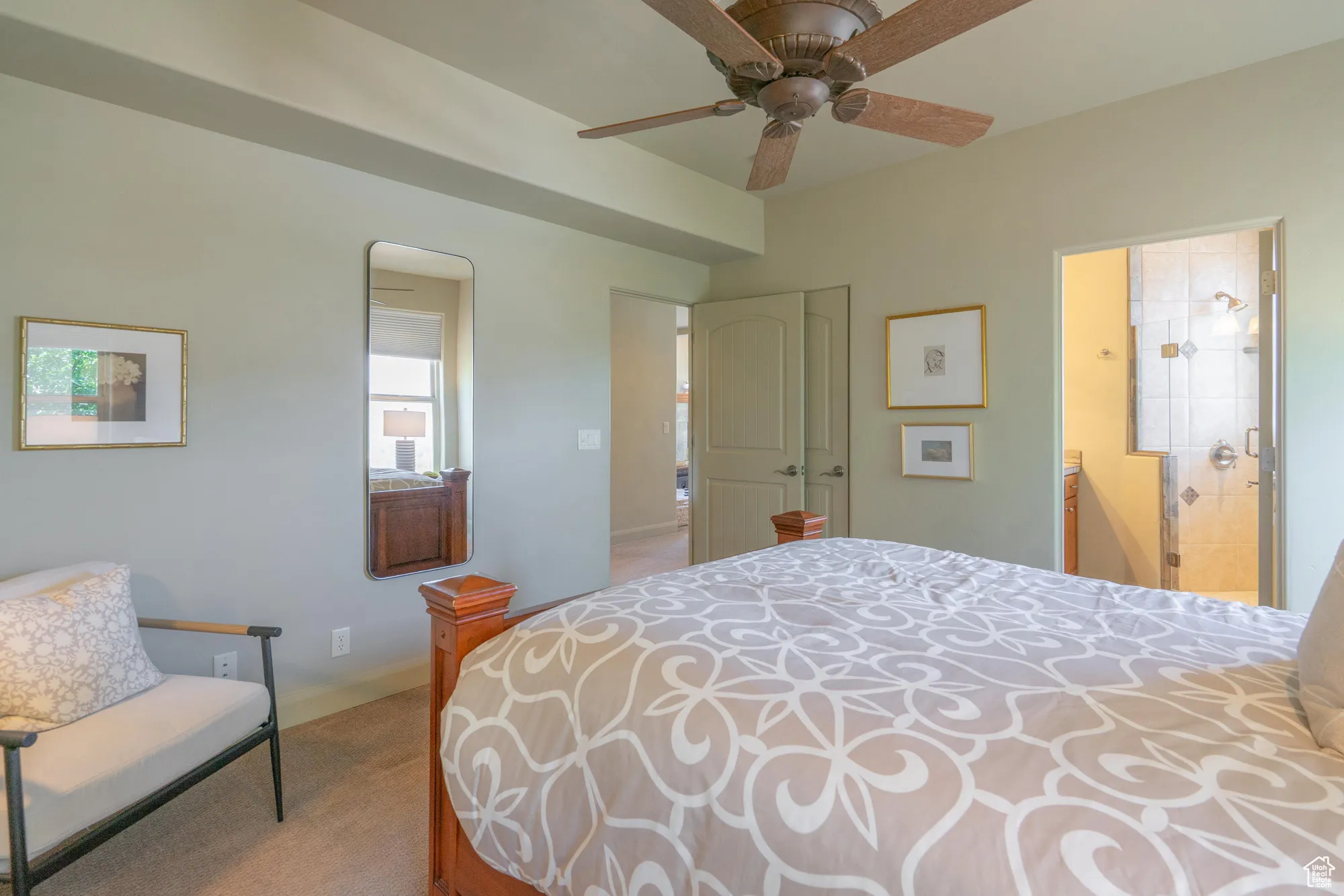 Bedroom with ensuite bath, light carpet, and a ceiling fan