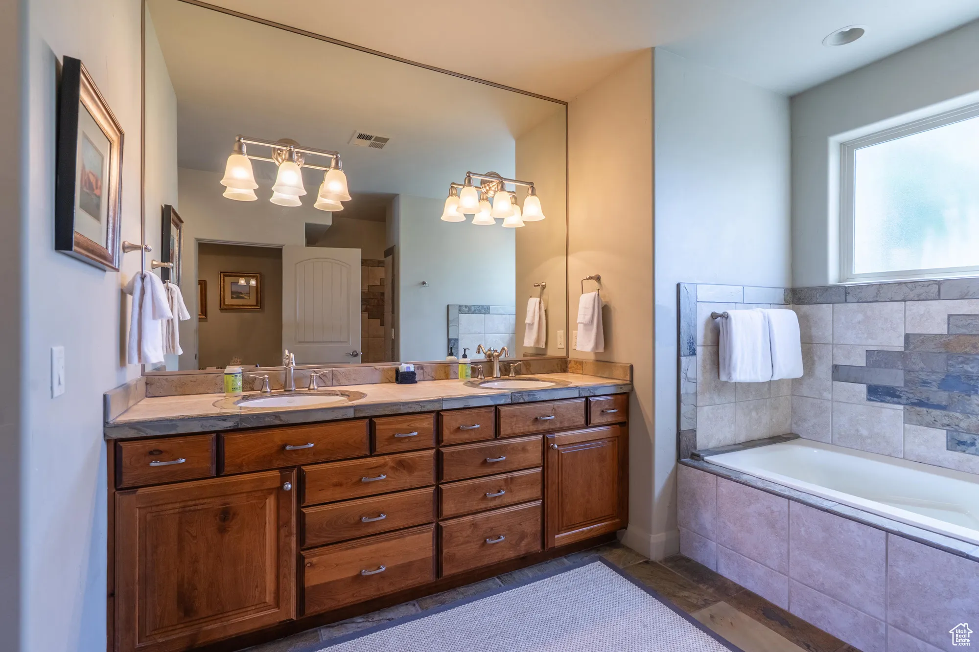 Bathroom featuring double vanity, a garden tub, and dark tile patterned floors