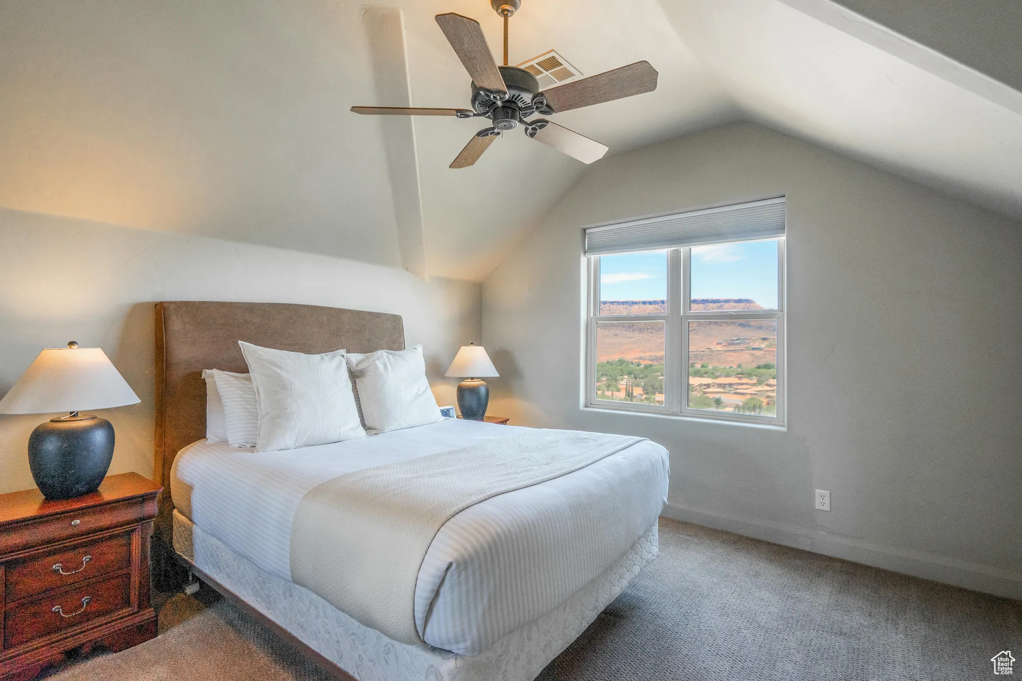 Carpeted bedroom featuring lofted ceiling and a ceiling fan