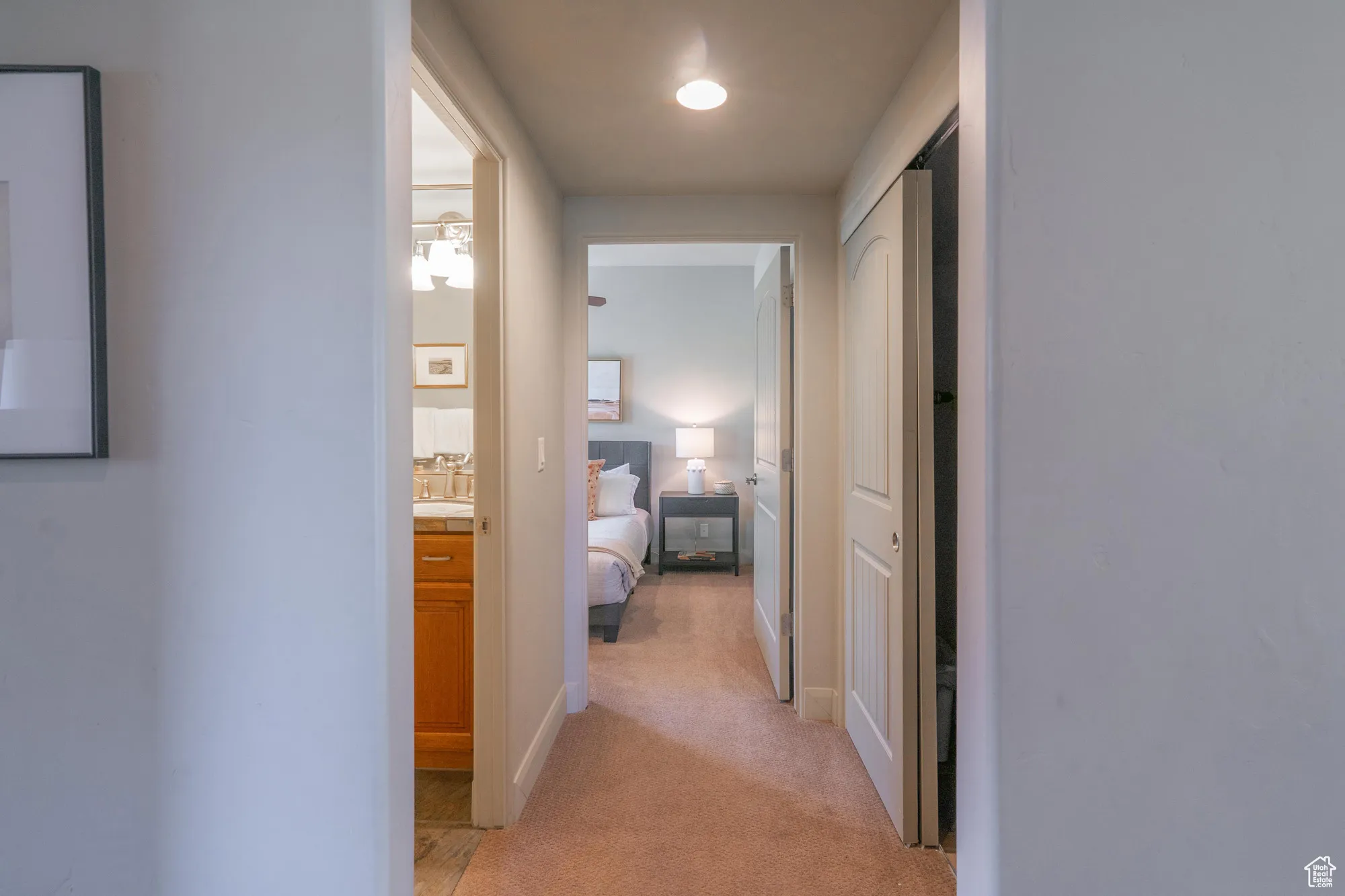 Hallway with light colored carpet and baseboards