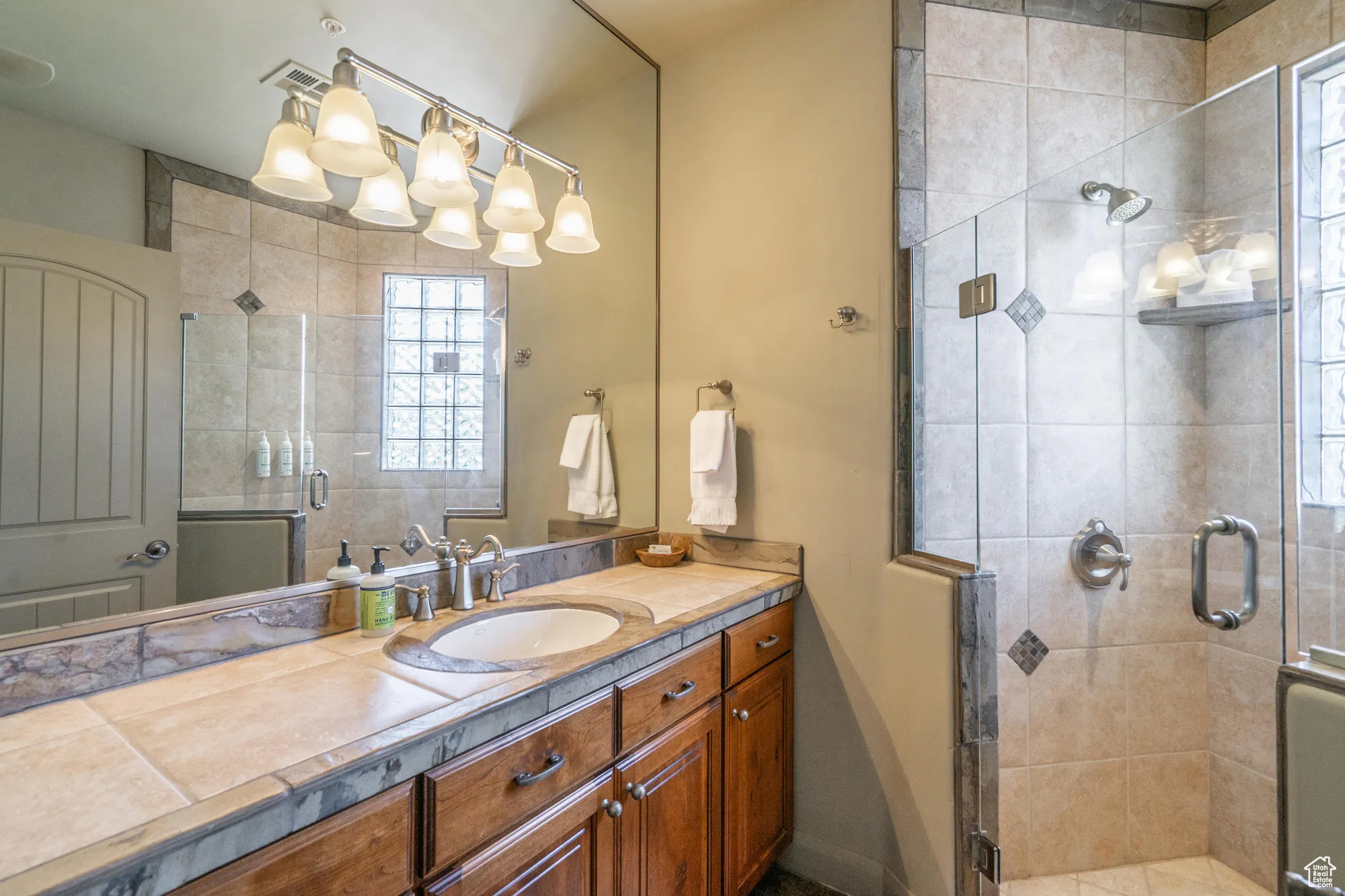 Bathroom with vanity, a stall shower, and plenty of natural light