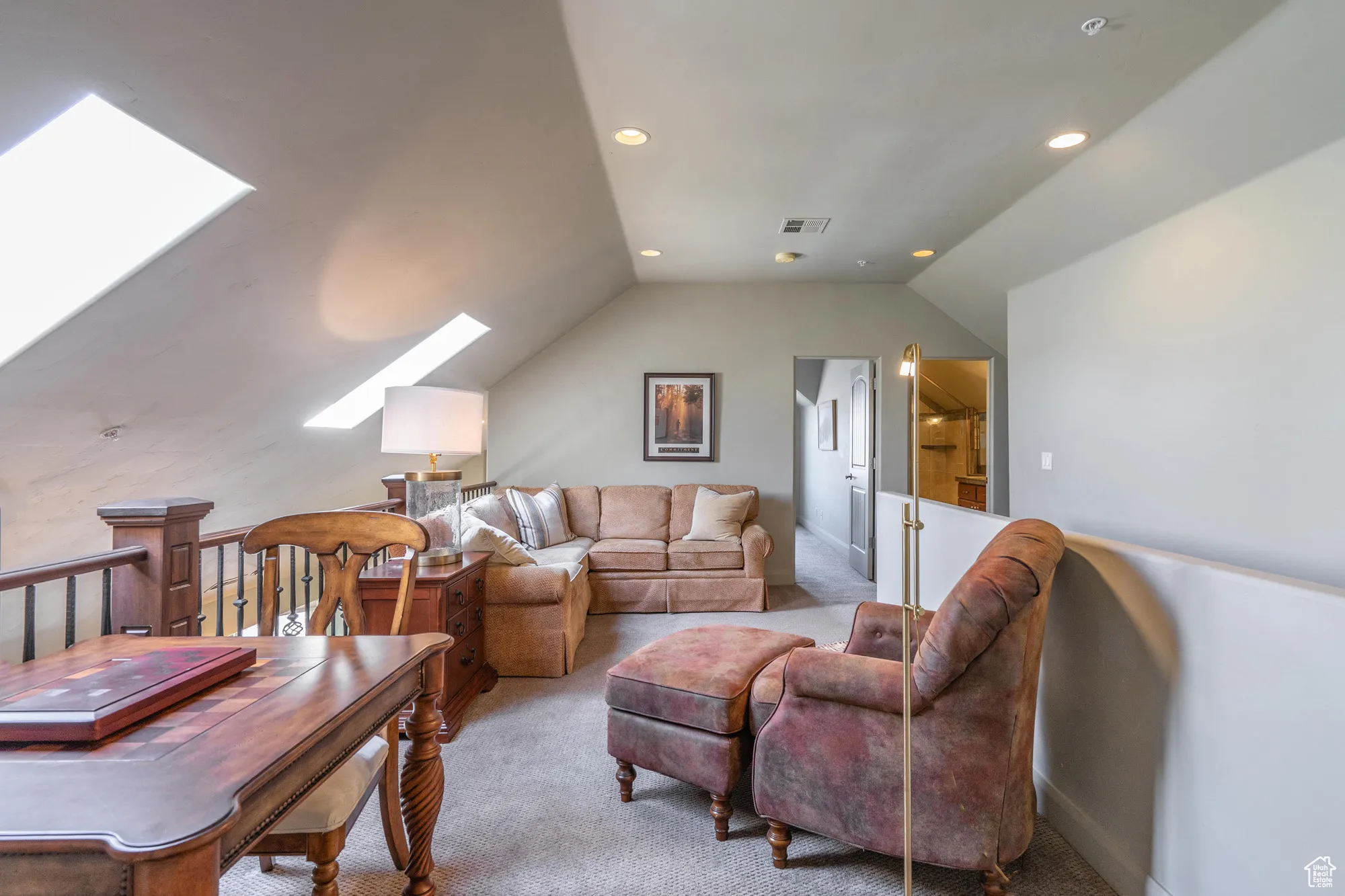 Carpeted living room with a skylight, vaulted ceiling, and recessed lighting