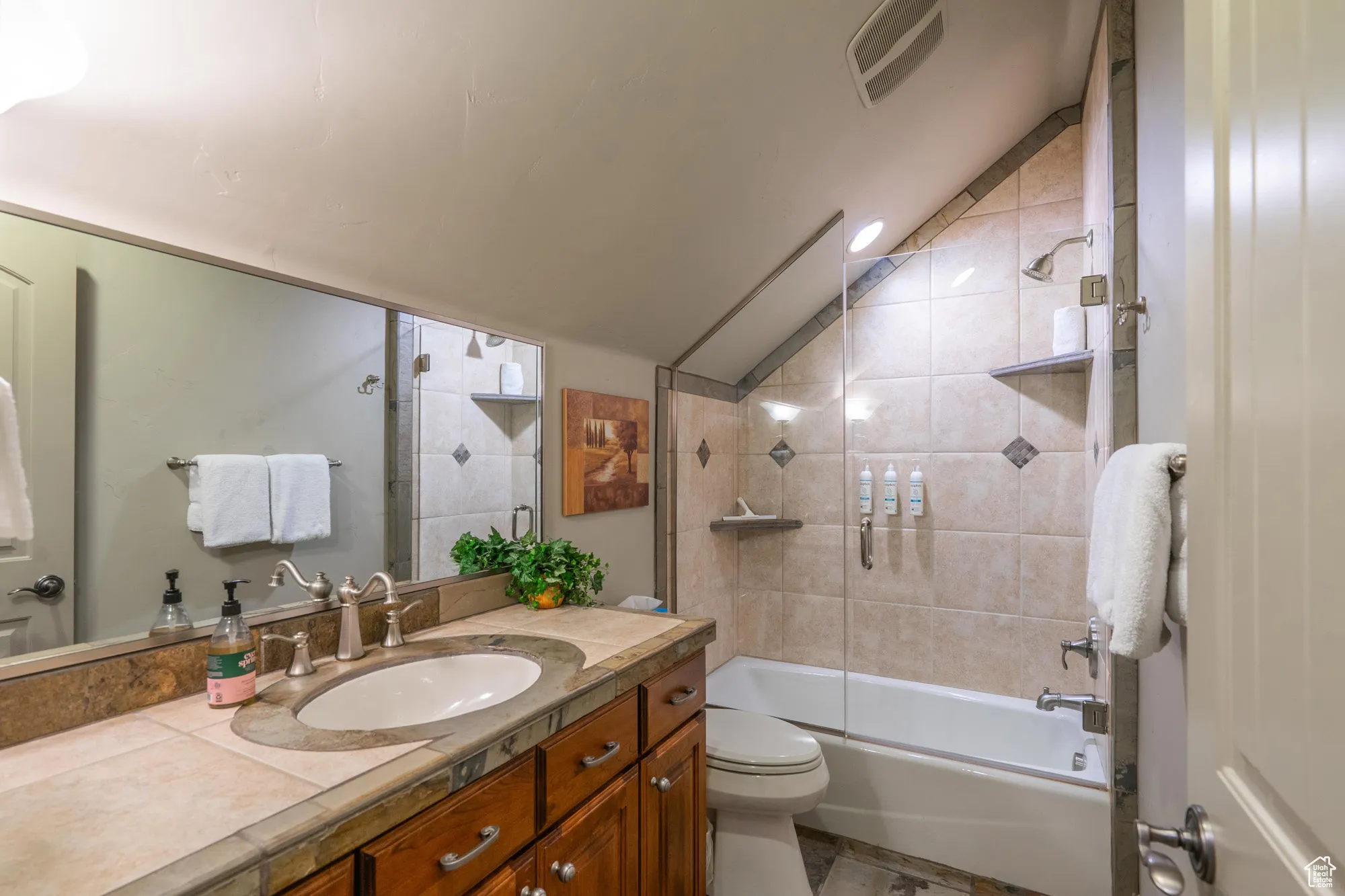 Full bath with bathing tub / shower combination, vanity, and lofted ceiling