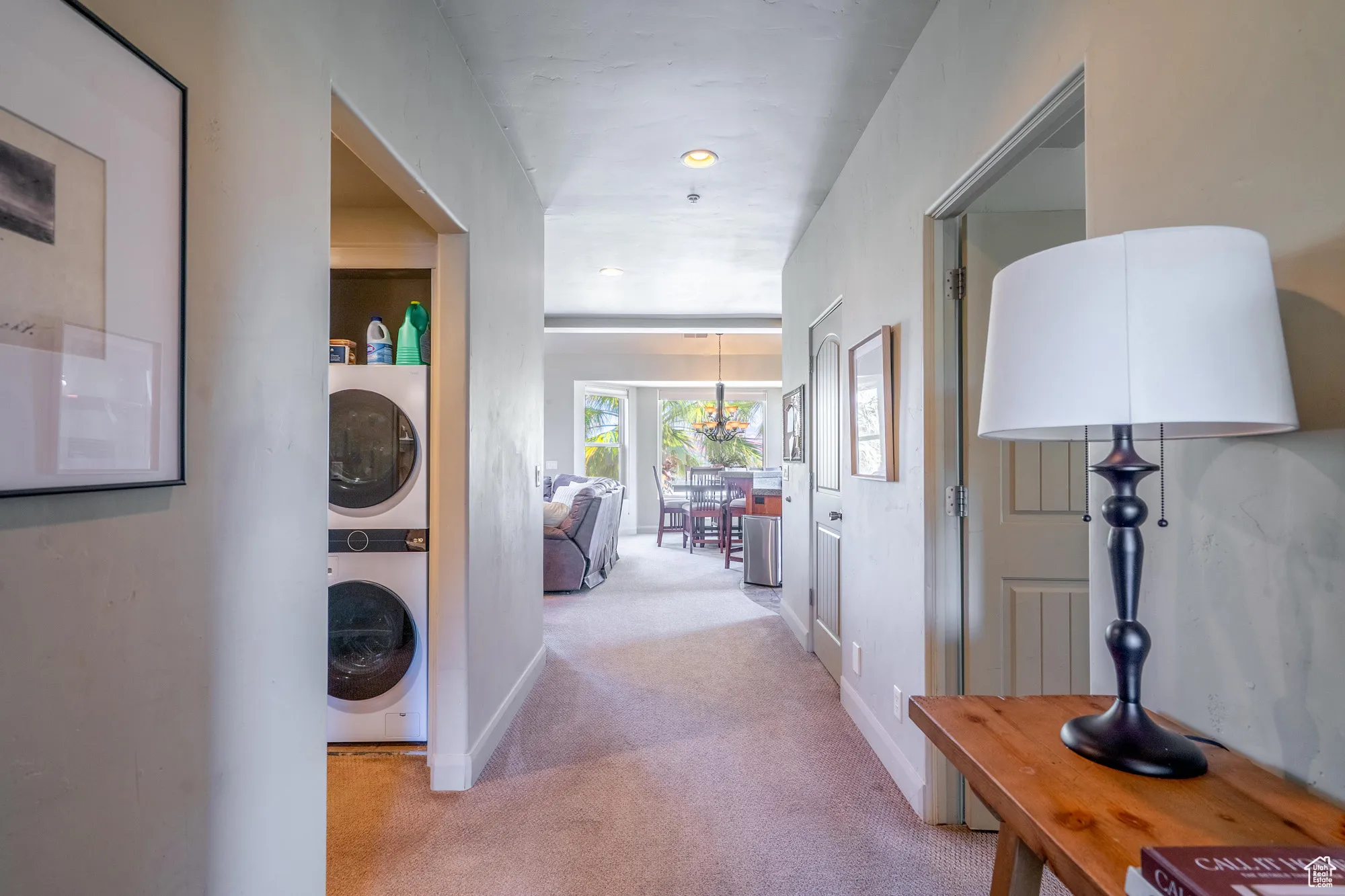 Hall with light carpet and stacked washing machine and dryer