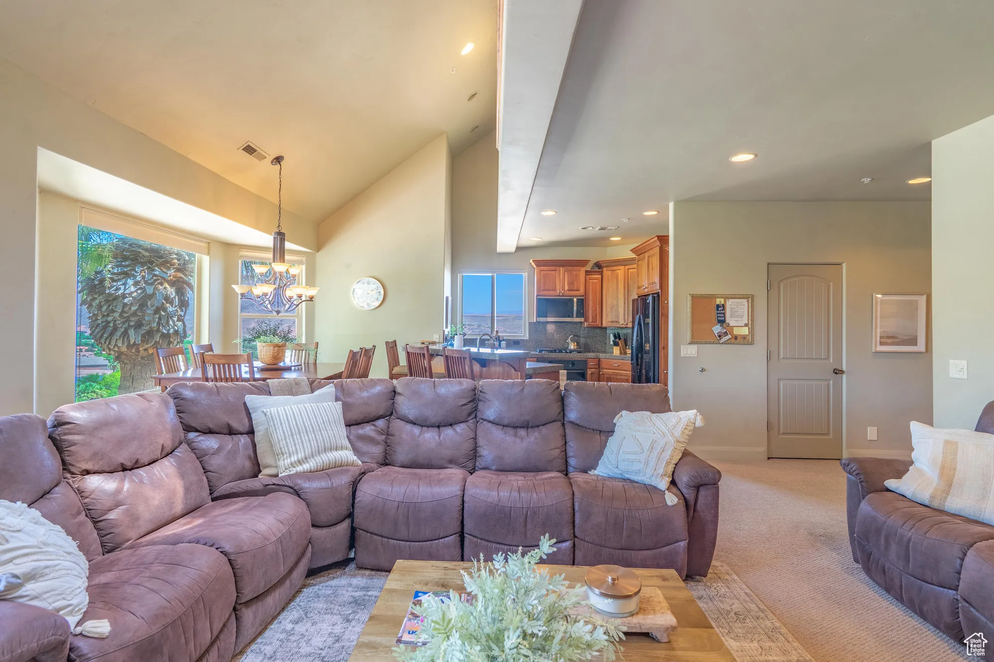 Living area featuring a chandelier, light colored carpet, high vaulted ceiling, and recessed lighting