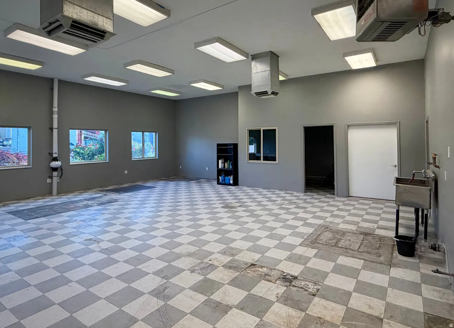 Spacious interior featuring checkerboard flooring, multiple windows, a utility sink, and recessed lighting fixtures