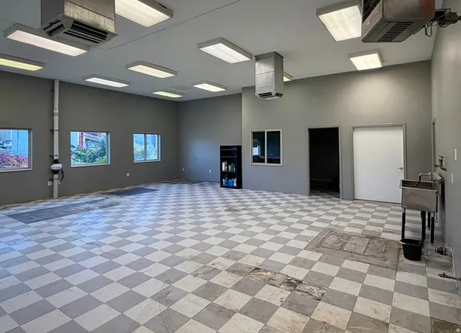 Spacious interior featuring checkerboard flooring, multiple windows, a utility sink, and recessed lighting fixtures