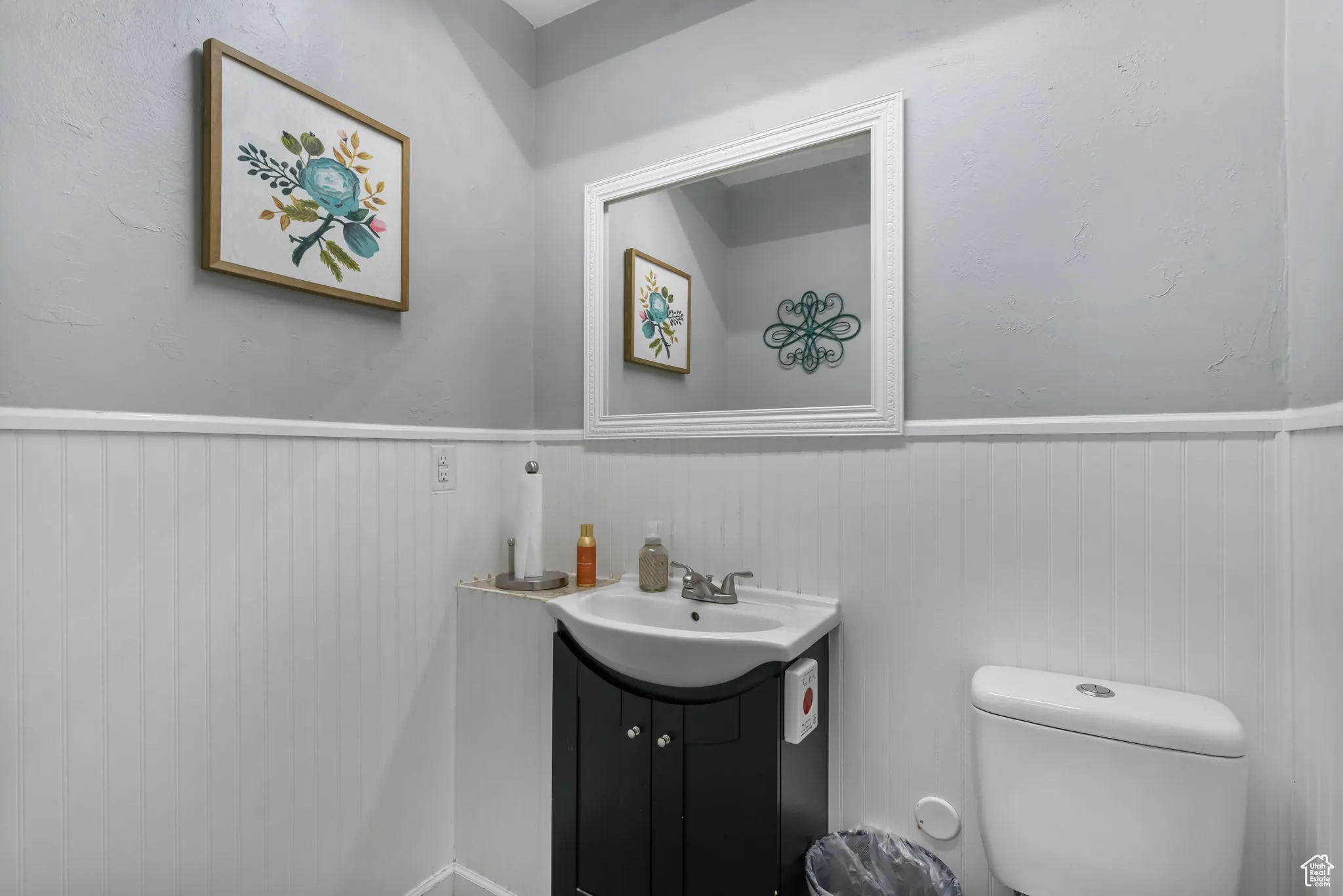 Bathroom featuring vanity, wainscoting, and a textured wall