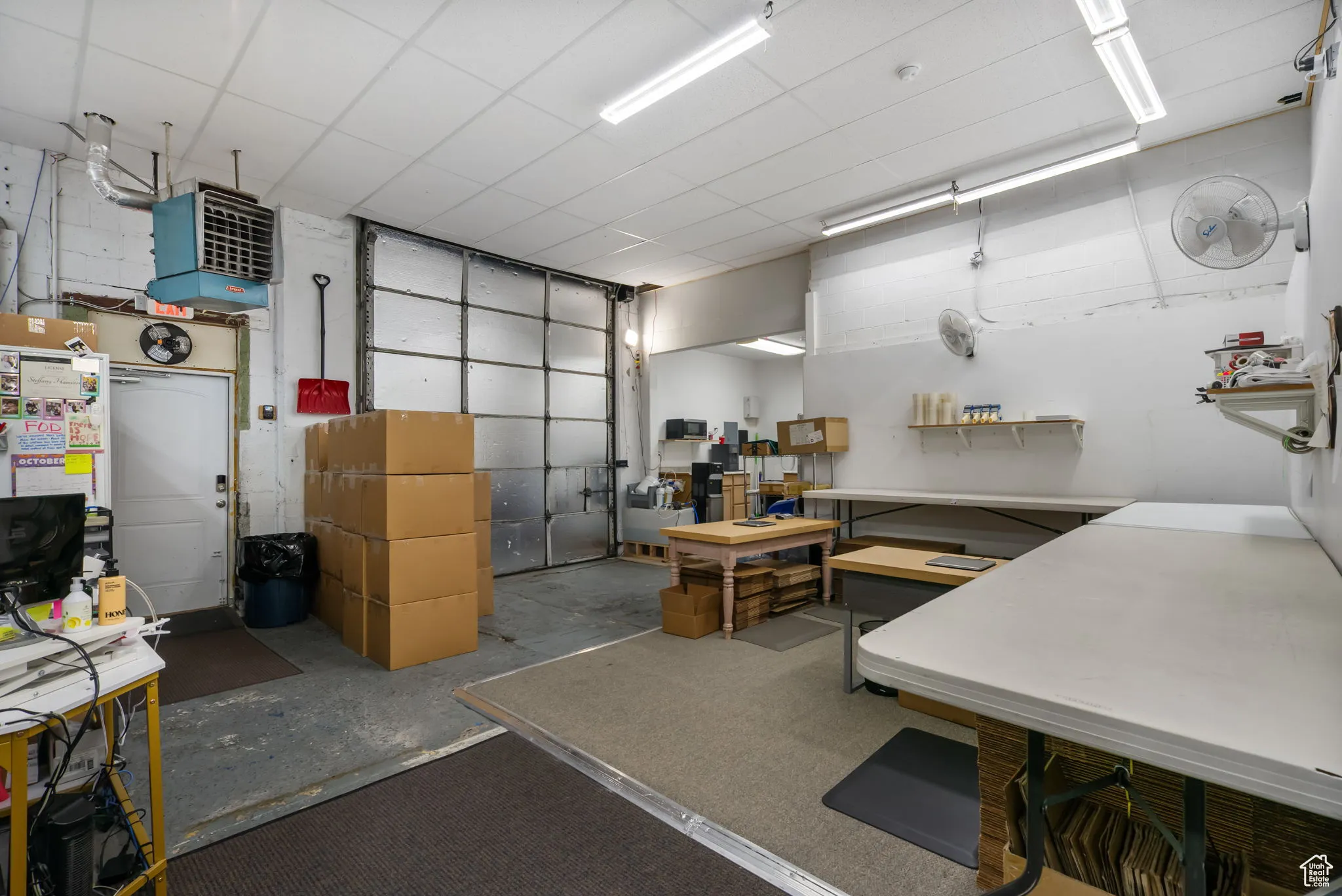 Misc room featuring concrete flooring, a paneled ceiling, and a heating unit