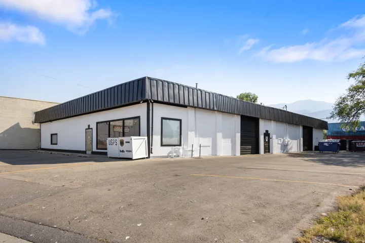 Commercial building featuring a white facade and a dark metal roof