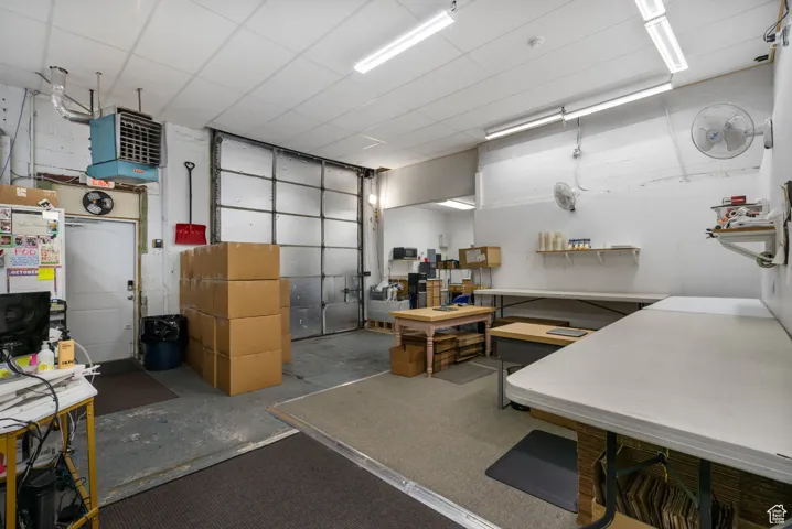 Misc room featuring concrete flooring, a paneled ceiling, and a heating unit