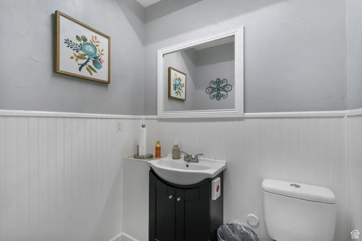 Bathroom featuring vanity, wainscoting, and a textured wall