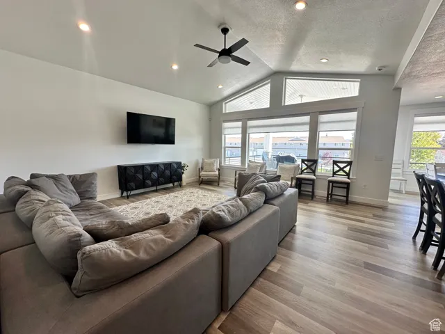 Living area with lofted ceiling, wood finished floors, recessed lighting, a textured ceiling, and ceiling fan