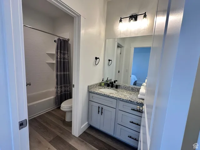 Ensuite bathroom featuring dark wood-style flooring, shower / bath combo, and vanity