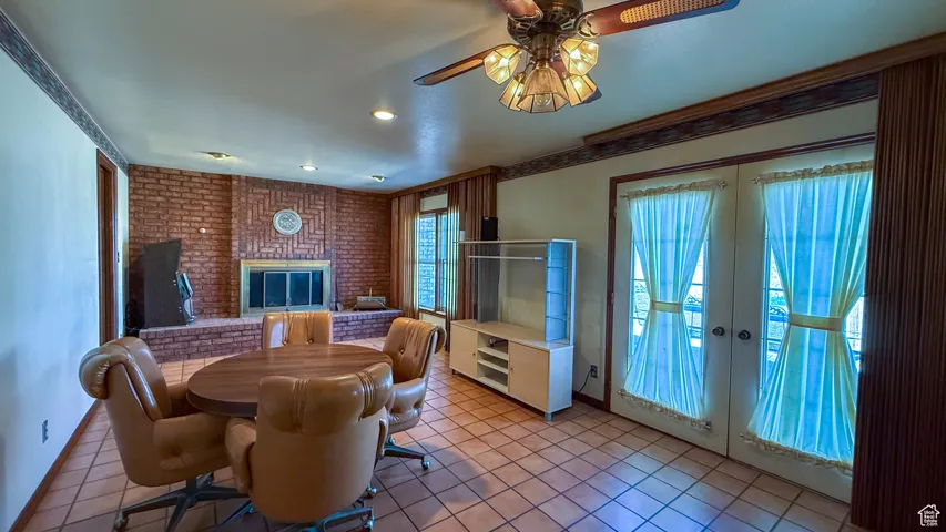 Dining space featuring ornamental molding, tile patterned flooring, brick wall, a fireplace, and french doors