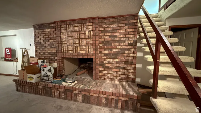 Unfurnished living room featuring stairs, concrete flooring, and a textured ceiling