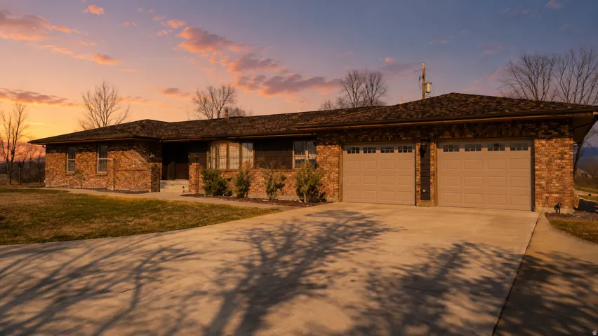 Brick exterior residence featuring a two-car garage with panel doors, a concrete driveway, and a shingle roof