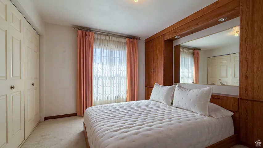 Carpeted bedroom featuring multiple windows and a closet