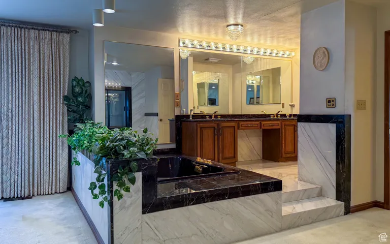 Full bathroom featuring double vanity, a bath, and light colored carpet