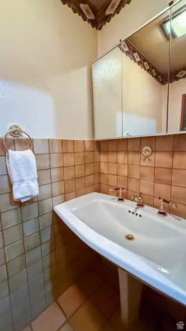 Bathroom featuring tile walls, tile patterned flooring, and a wainscoted wall