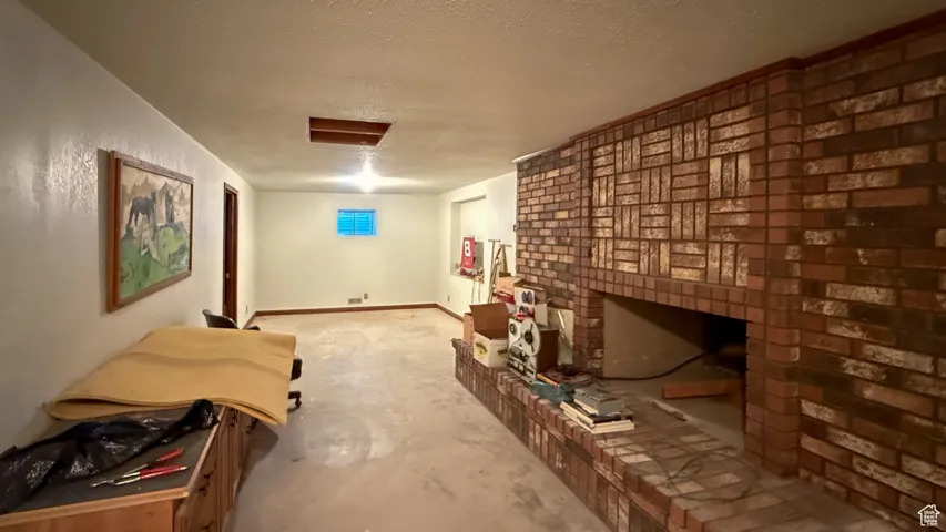 Living room featuring a textured ceiling and unfinished concrete flooring