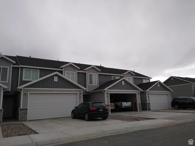 View of front of house with stone siding, driveway, board and batten siding, and a garage