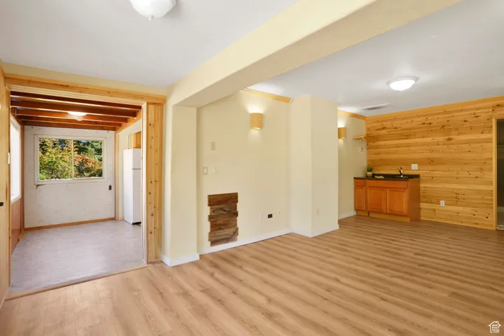 Unfurnished living room with wooden walls and light wood-type flooring