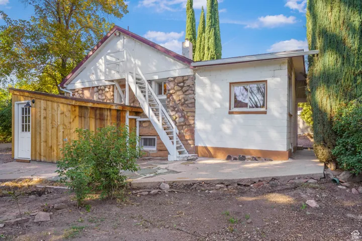 Back of house with stairway, a chimney, a patio area, and concrete block siding